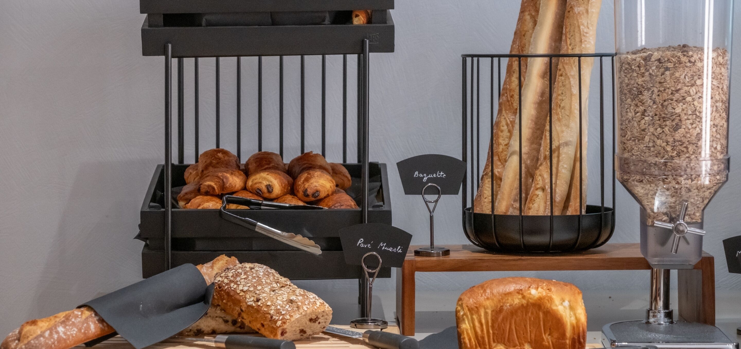 Une vitrine de boulangerie présentant diverses sortes de pains et de viennoiseries, notamment des baguettes et une trancheuse à pain.