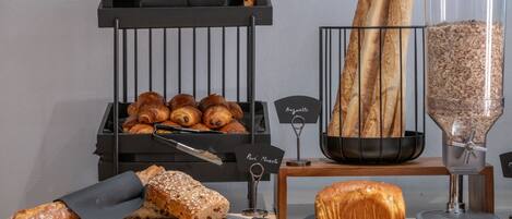 Une vitrine de boulangerie présentant diverses sortes de pains et de viennoiseries, notamment des baguettes et une trancheuse à pain.