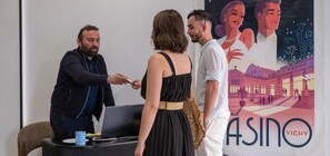 Eine Gruppe von Personen an einem Schreibtisch mit einem Laptop, ein Plakat im Hintergrund und ein Tisch mit einer Tasse und einem Notizbuch.