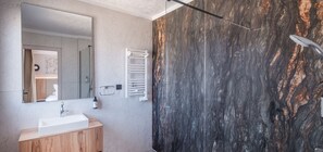 Ein modernes Badezimmer mit Marmorwand, Waschbecken in Weiß und einem Handtuchhalter.