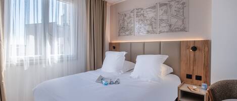 Una habitación de hotel con una cama grande, una mesita de noche, una silla y una pared decorada con obras de arte.