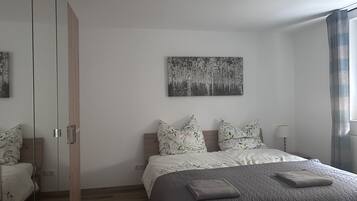 Une chambre à coucher avec un lit, une armoire, un tableau et une fenêtre avec des rideaux.