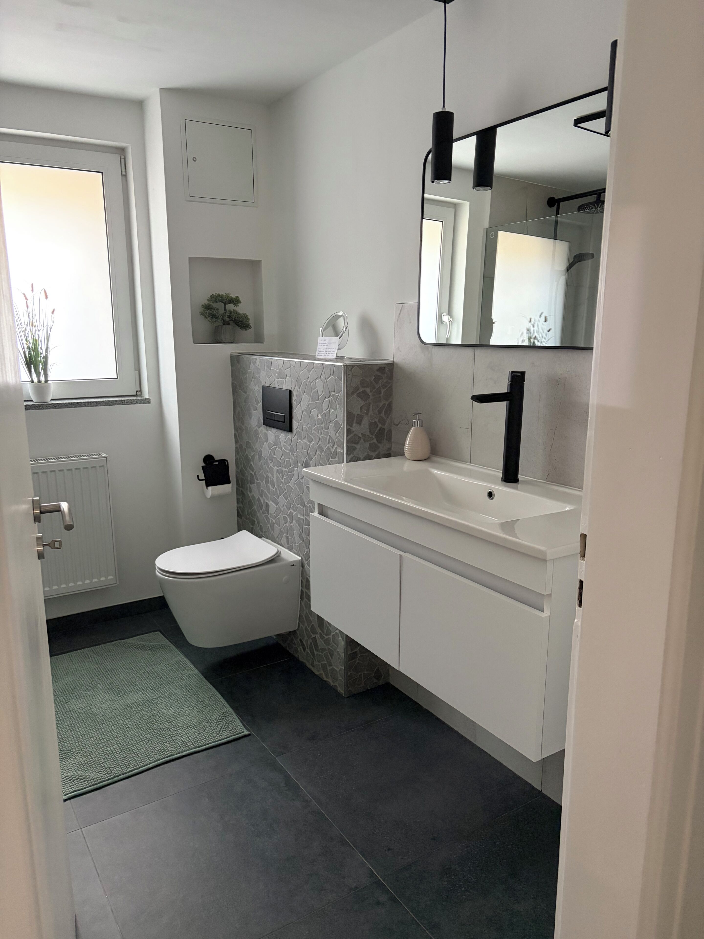 Une salle de bain moderne avec des toilettes, un lavabo et un miroir.
