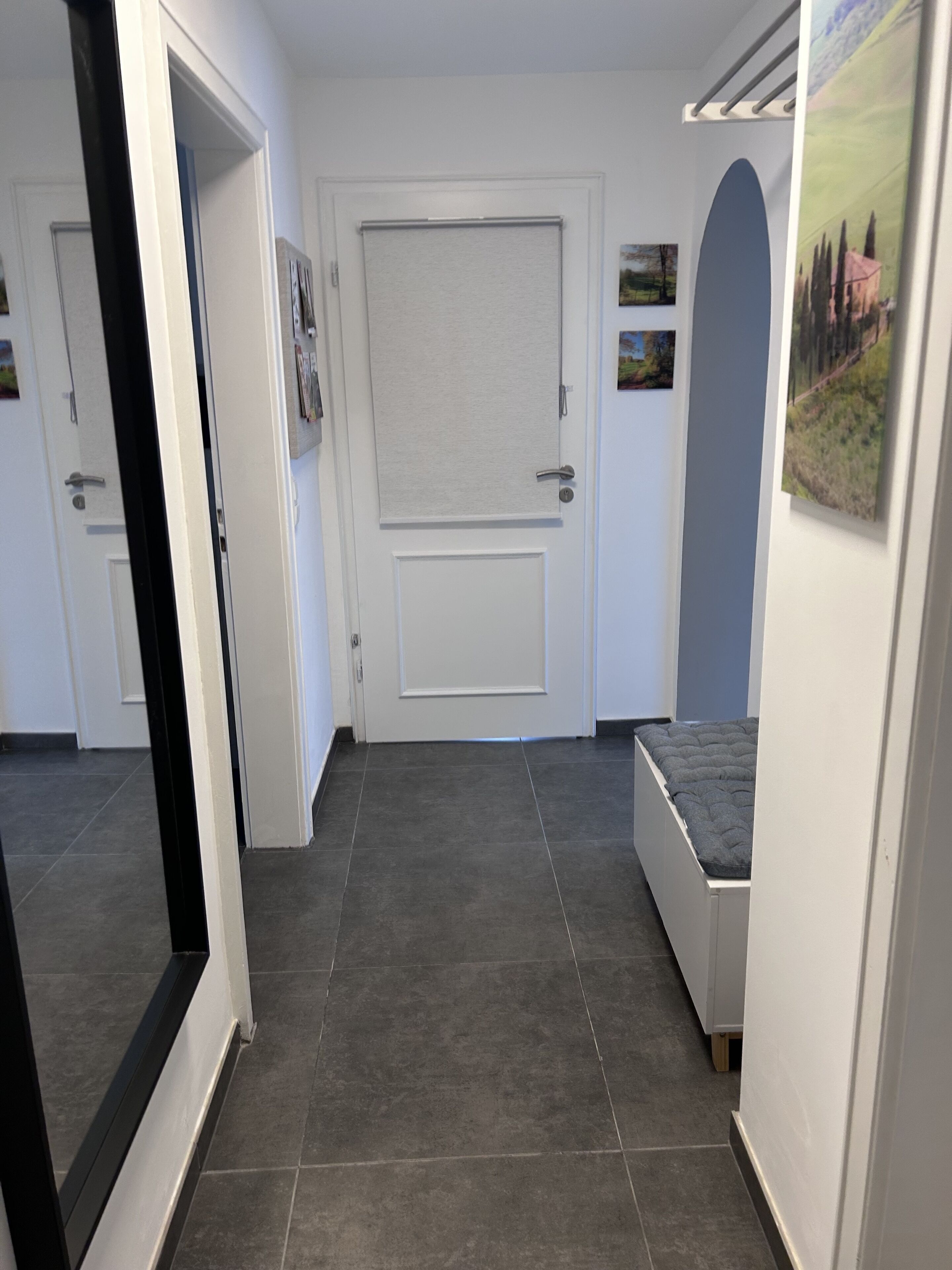 Ein Flur mit einer geschlossenen Tür, einer kleinen Bank und einem an der Wand befestigten Bilderrahmen.