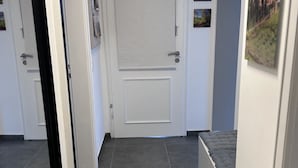 A hallway with a closed door, a small bench, and a wall-mounted picture frame.