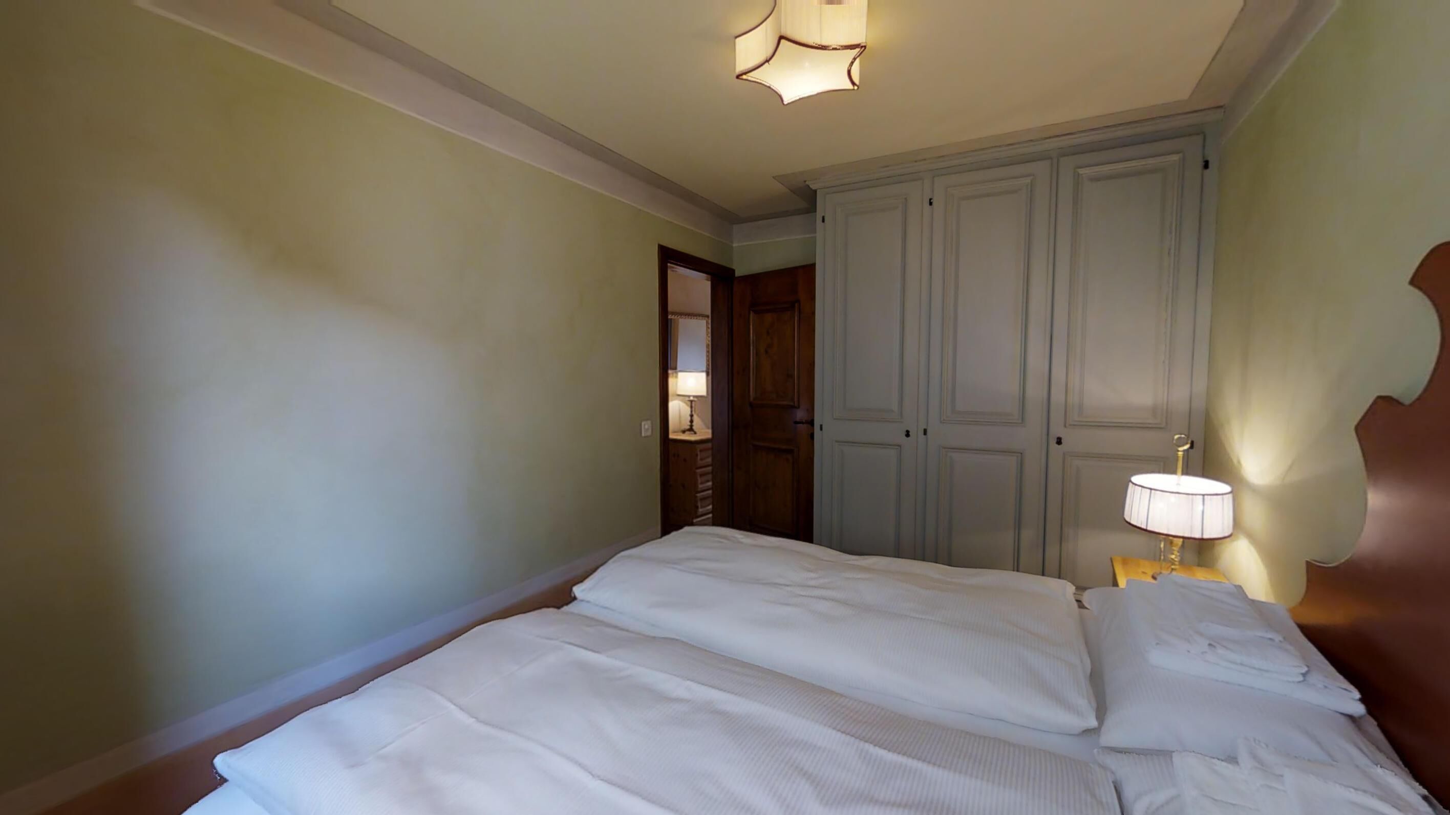 Une chambre à coucher avec un lit double, une table de chevet avec une lampe et une armoire à deux portes.