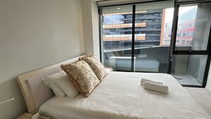 Una moderna camera d'albergo con un letto grande, un comodino con un telefono e una finestra che si affaccia sulla città.