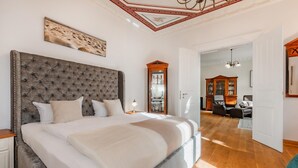 Una cama grande con cabecera acolchada, una mesita de noche y una mesilla.