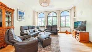 Un salón amplio con sofás de cuero, una mesa de centro, un televisor y un mueble de madera.