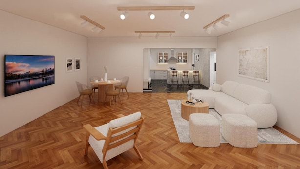 Un salón moderno con piso de madera en patrón de espiga, un sofá blanco, una mesa de comedor con sillas y una cocina al fondo.