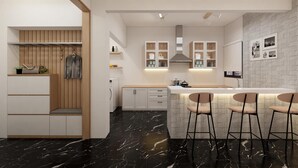 Una cocina moderna con piso de mármol, armarios de madera, una isla central con taburetes de bar y estufa empotrada.
