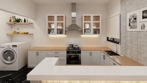 Una cocina moderna con una isla central, horno integrado y microondas. Hay armarios blancos con puertas de vidrio, lavadora y un lavaplatos.