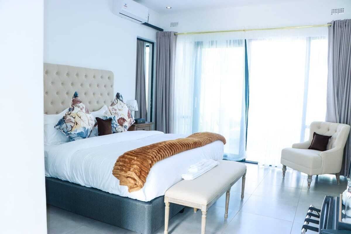 Een moderne hotelkamer met een groot bed, een bankje, een stoel en uitzicht op de omgeving.