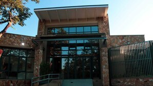 Un edificio moderno con fachada de piedra, ventanas de vidrio amplias y una puerta de metal.