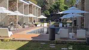 Un área junto a la piscina con mobiliario exterior y sombrillas.