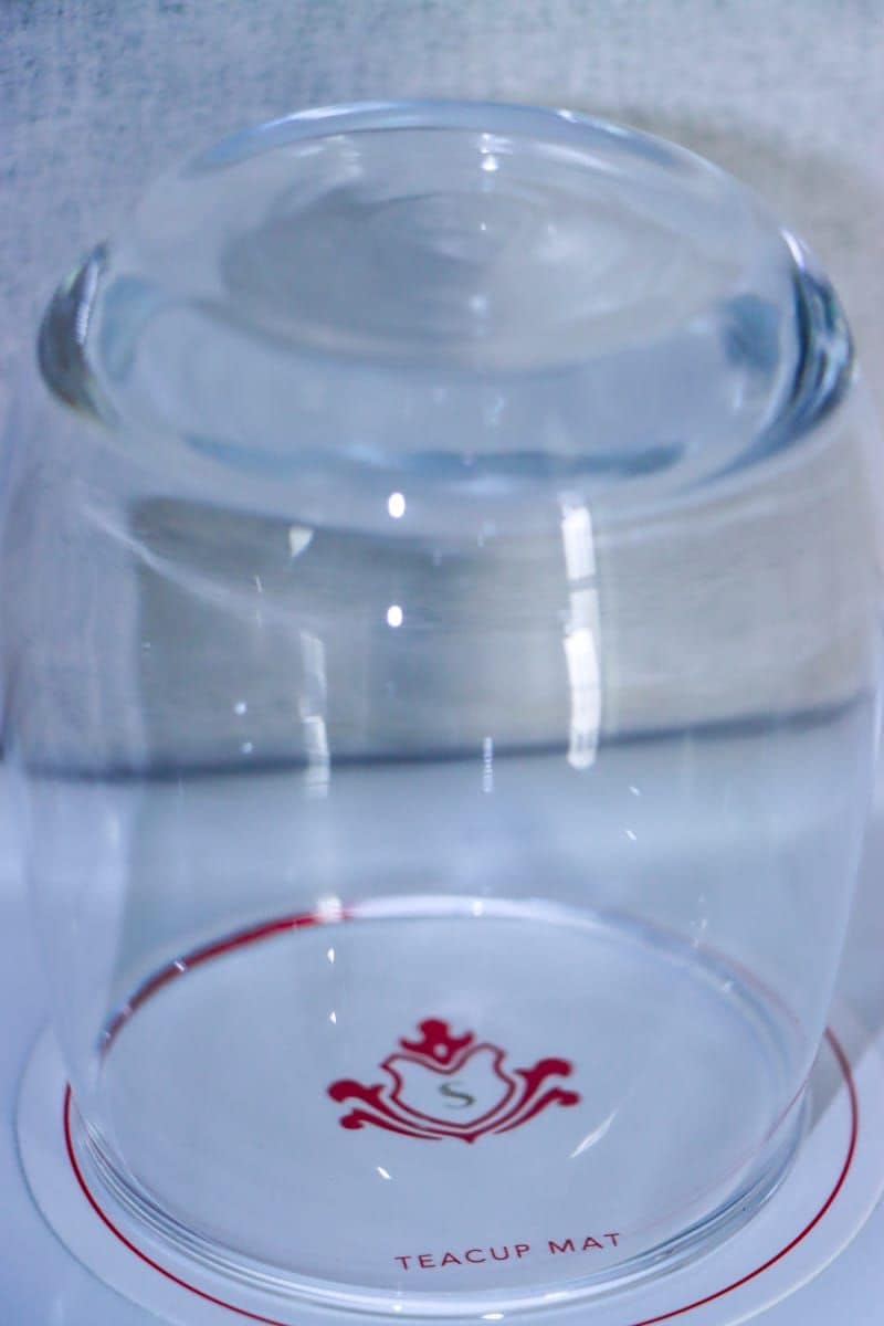 A clear teacup mat with a red logo and the text "TEACUP MAT" on a white surface.