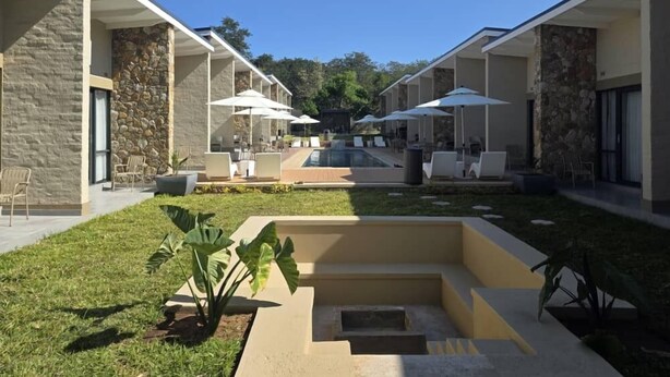 Un espacio exterior moderno con piscina, sillas de descanso y sombrillas.