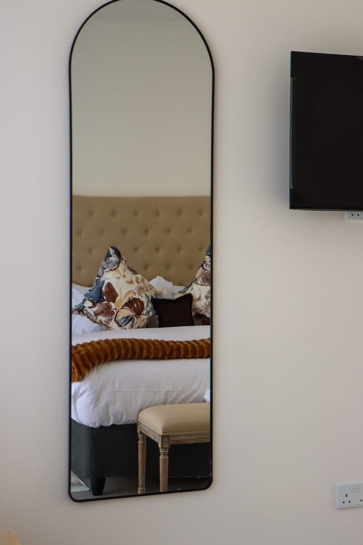 Ein Schlafzimmer mit einem Bett, einem Nachttisch und einem an der Wand befestigten Fernseher.