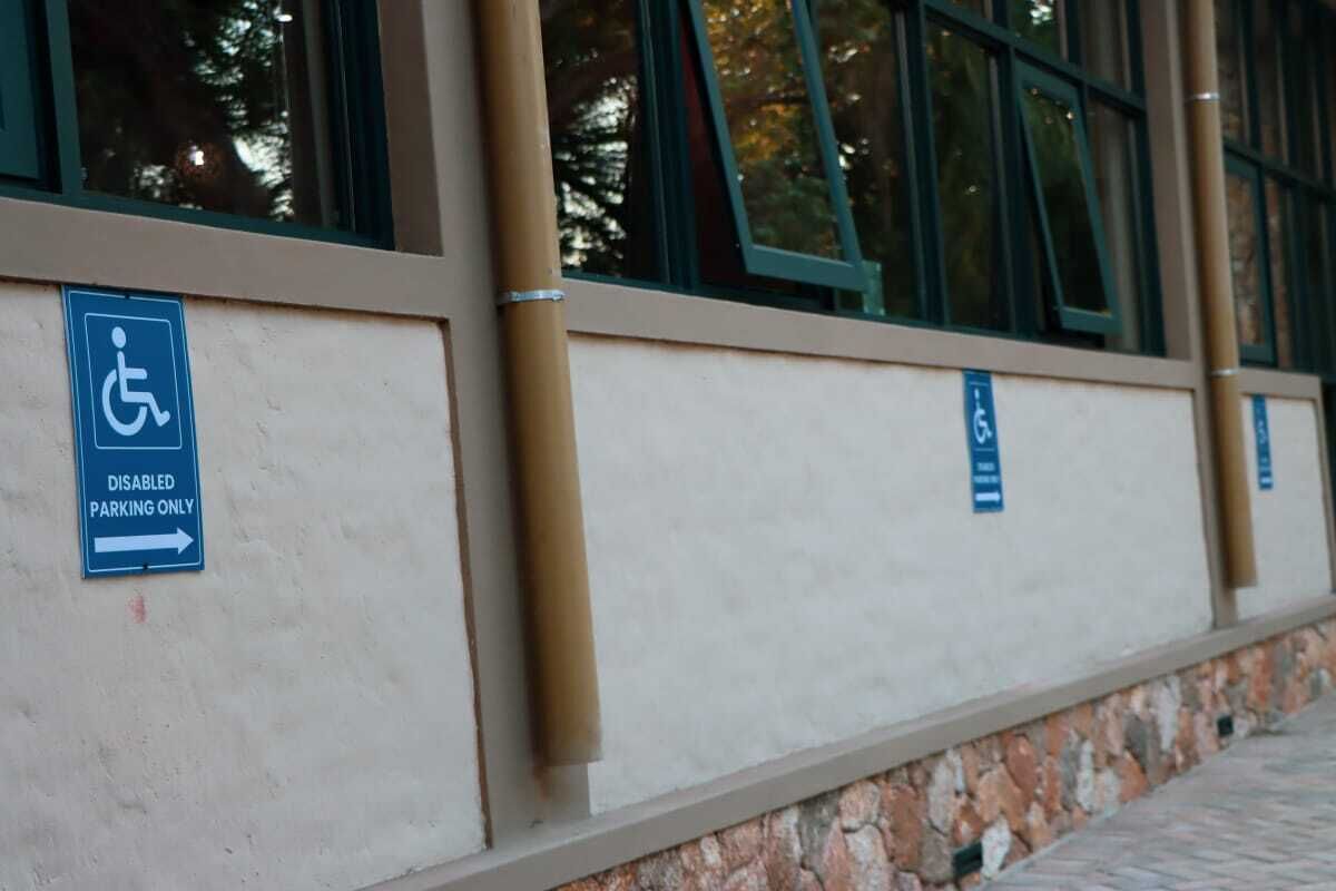 A building exterior with a disabled parking sign and a directional arrow.