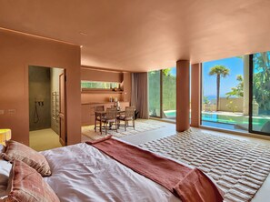 Un dormitorio moderno con una cama grande, un comedor y vista a una piscina.