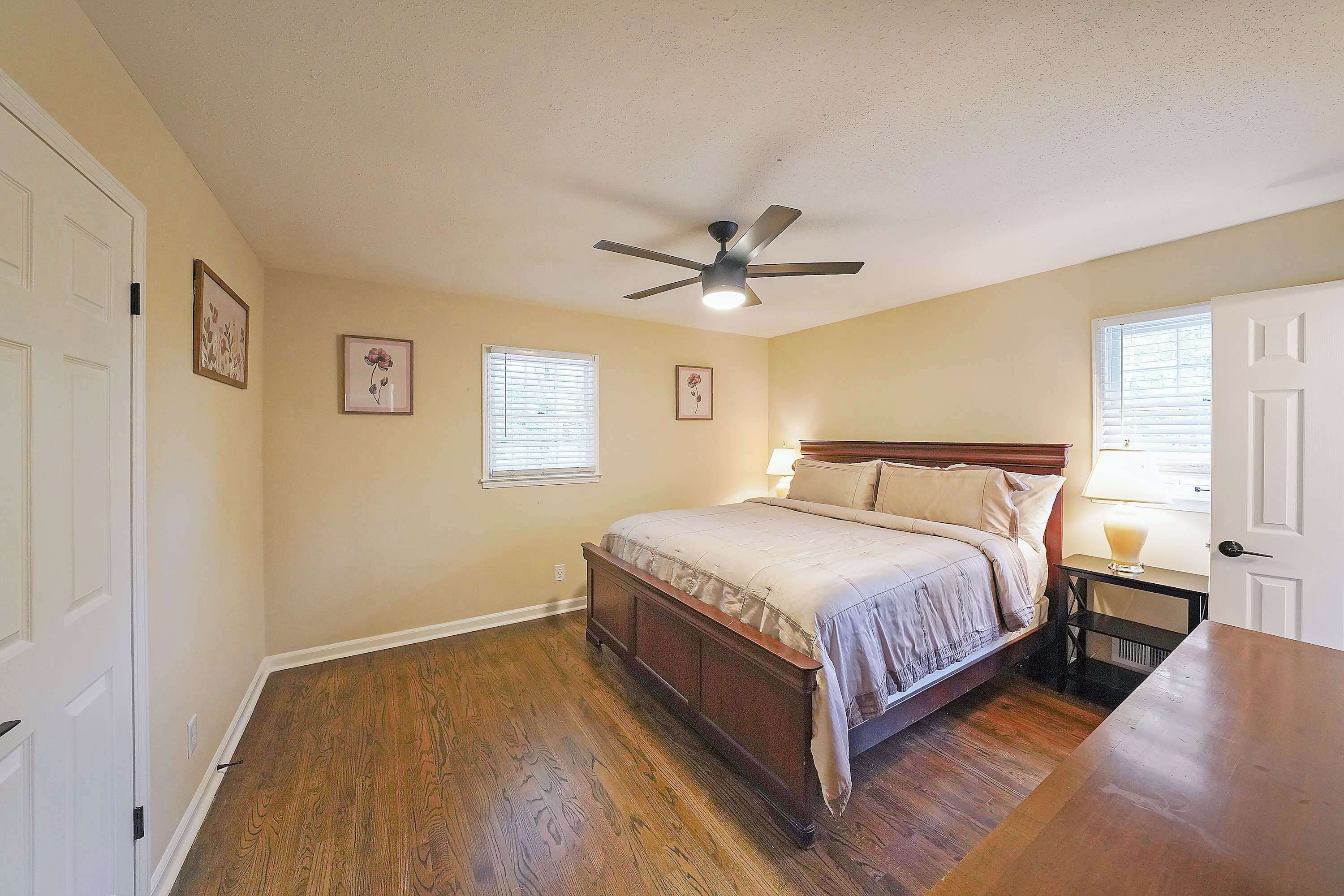 A bedroom with a bed, a ceiling fan, and a window with blinds.