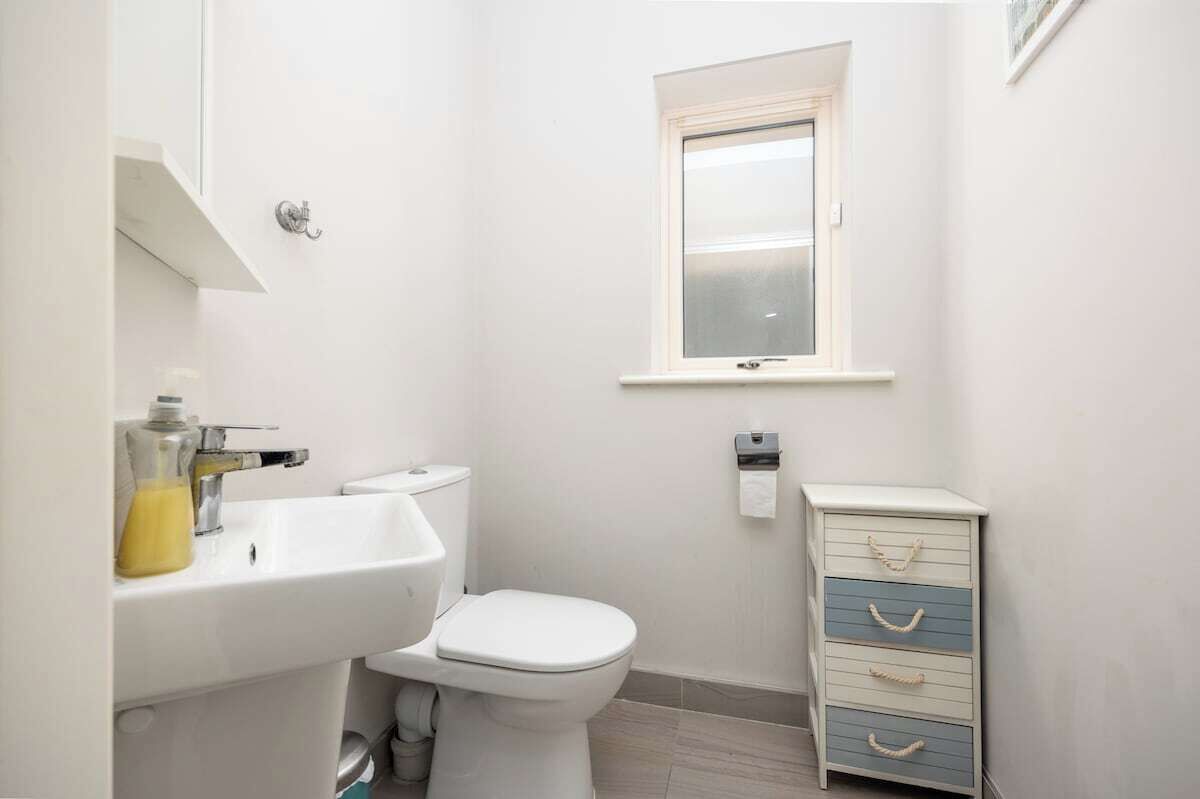 A small, clean bathroom with a toilet, sink, and a small cabinet.
