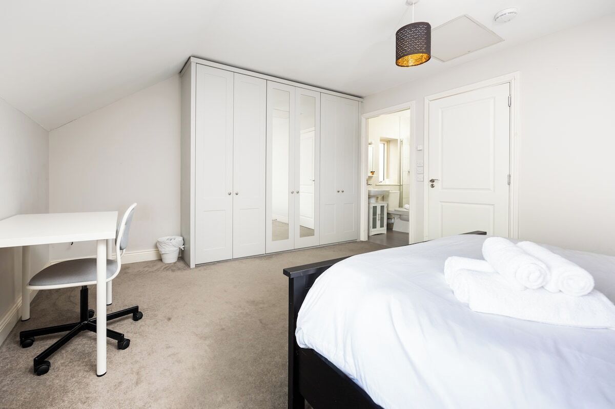 A bedroom with a bed, a desk, and a wardrobe.