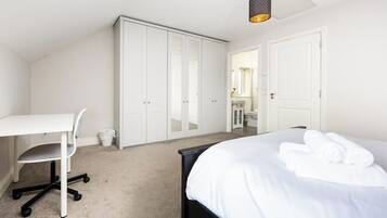A bedroom with a bed, a desk, and a wardrobe.