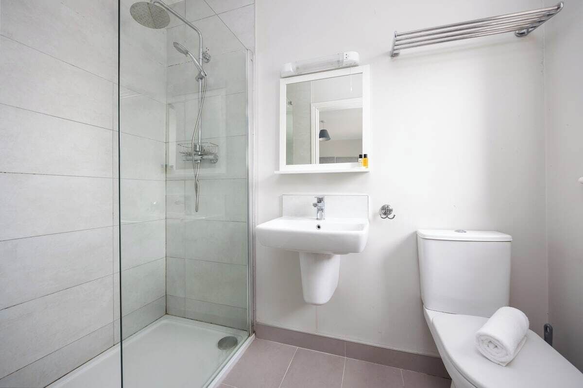 A modern bathroom with a glass-enclosed shower, a white sink, and a toilet.