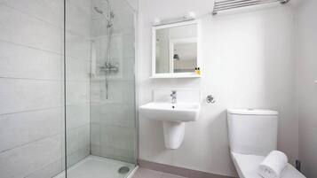 A modern bathroom with a glass-enclosed shower, a white sink, and a toilet.