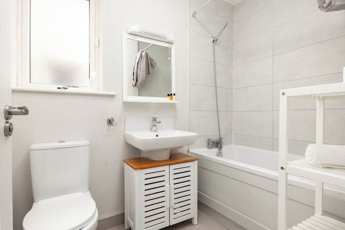 A modern bathroom with a toilet, sink, mirror, and shower.