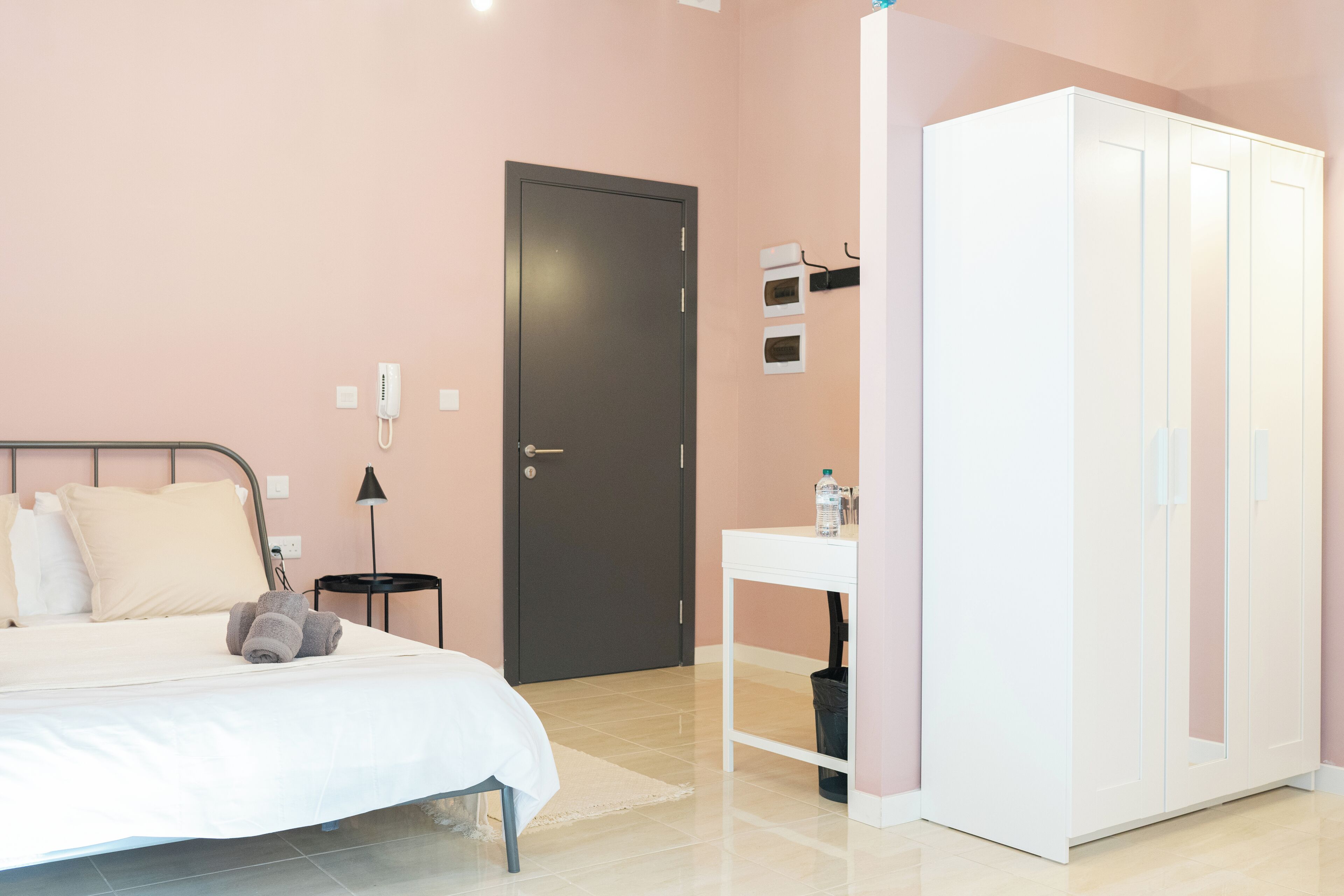 Un dormitorio con cama, armario, mesita de noche, lámpara y puerta.