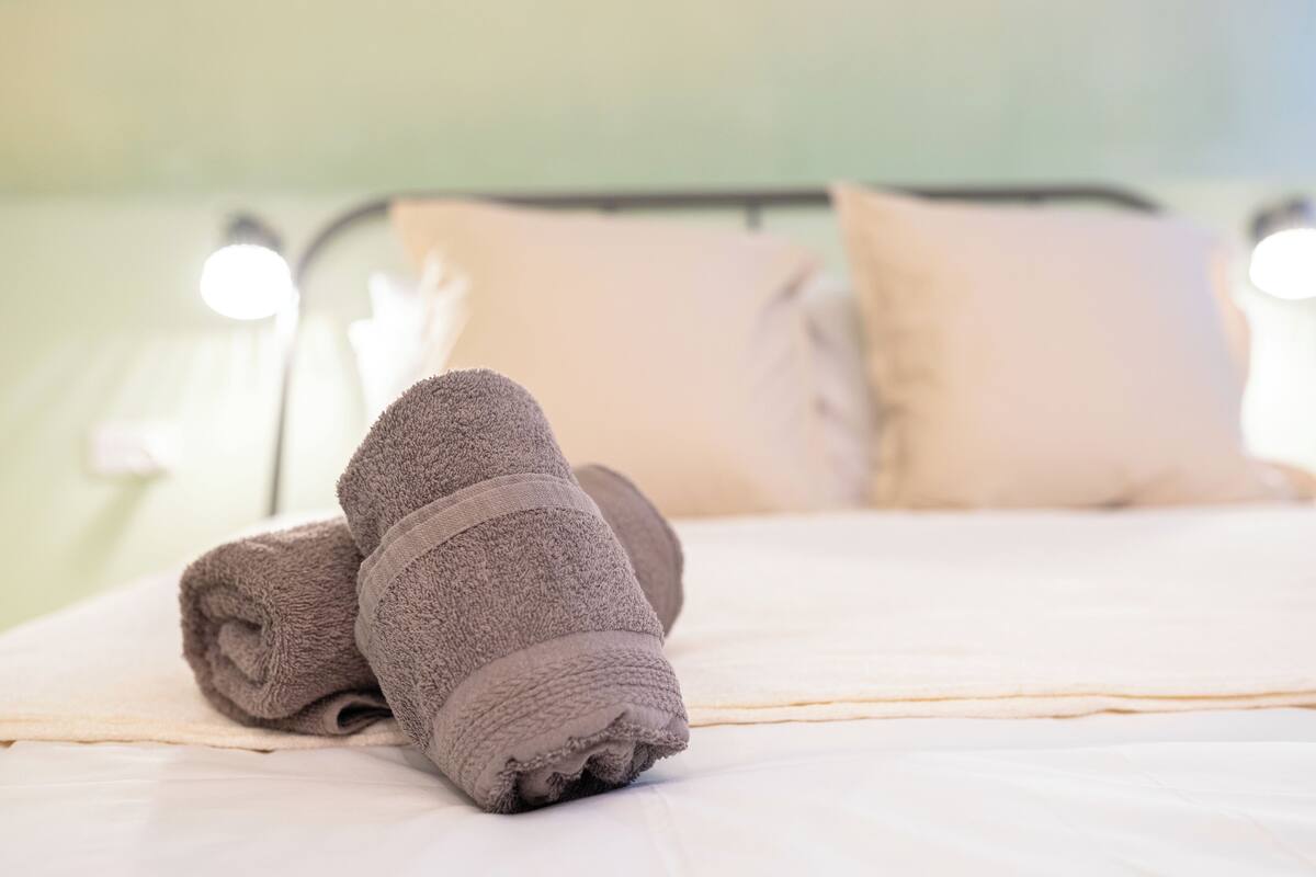 A neatly made bed with a folded towel and a pillow.