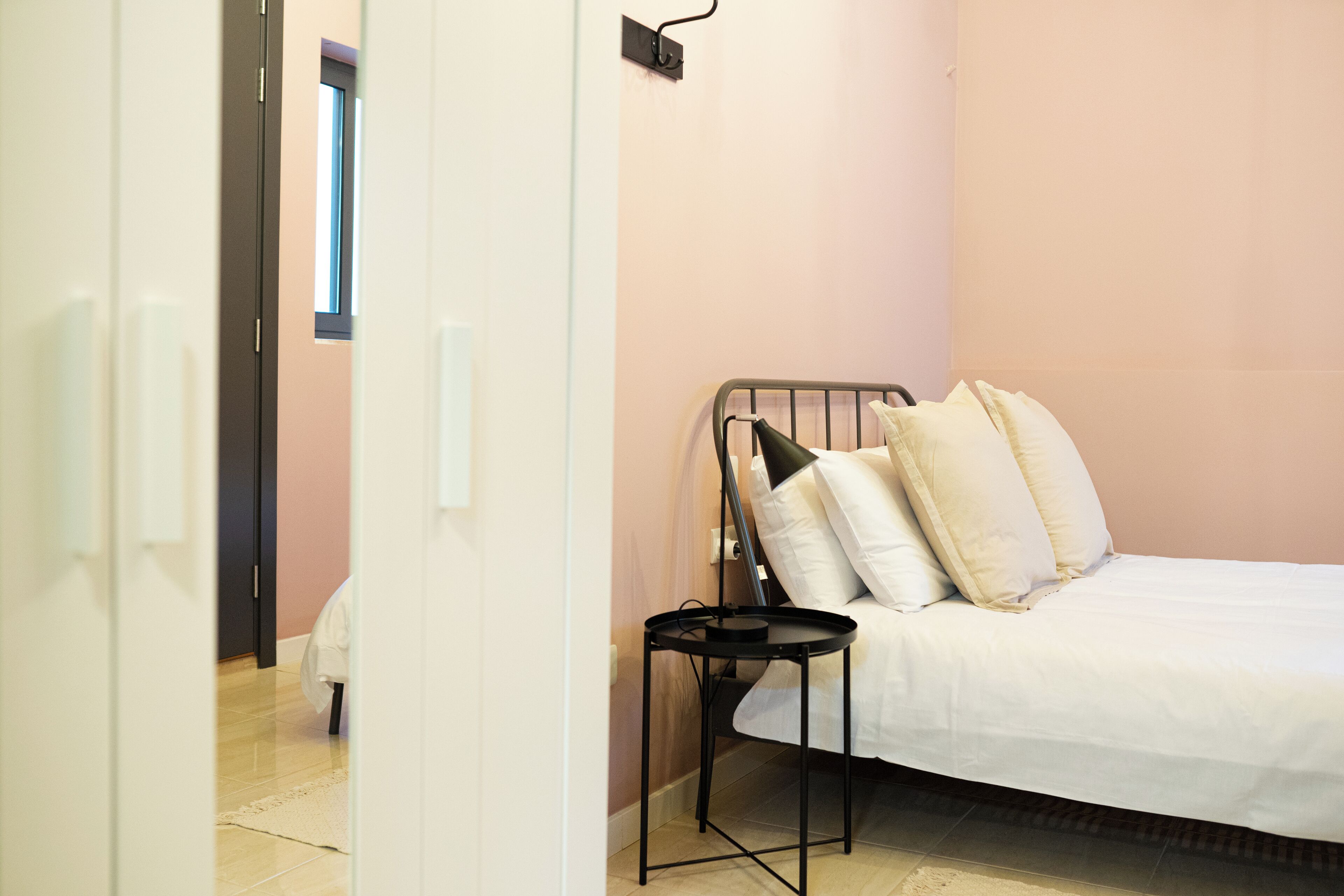 A bedroom with a bed, a bedside table, and a window.