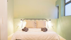 Een keurig opgemaakt bed met witte beddengoed en twee kussens, een metalen hoofdbord en twee wandlampen.
