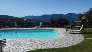 A swimming pool with a slide, surrounded by stone tiles and lounge chairs, with mountains in the background. - Rosemary 1 apartment in Agra with pool (Agra)