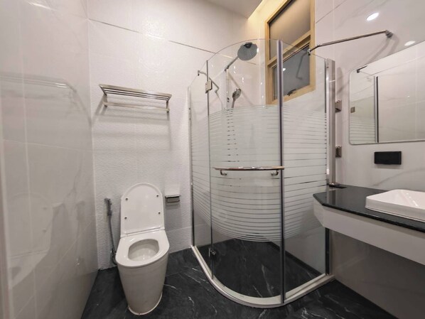 Uma casa de banho moderna com chuveiro em cabine de vidro, sanita e lavatório.