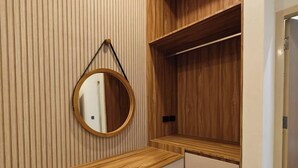 Un baño moderno con tocador de madera, un espejo redondo y un armario empotrado.