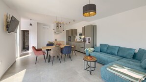 Ein modernes Wohnzimmer mit einer Couch, einem Esstisch, Stühlen und einer Küchenzeile.
