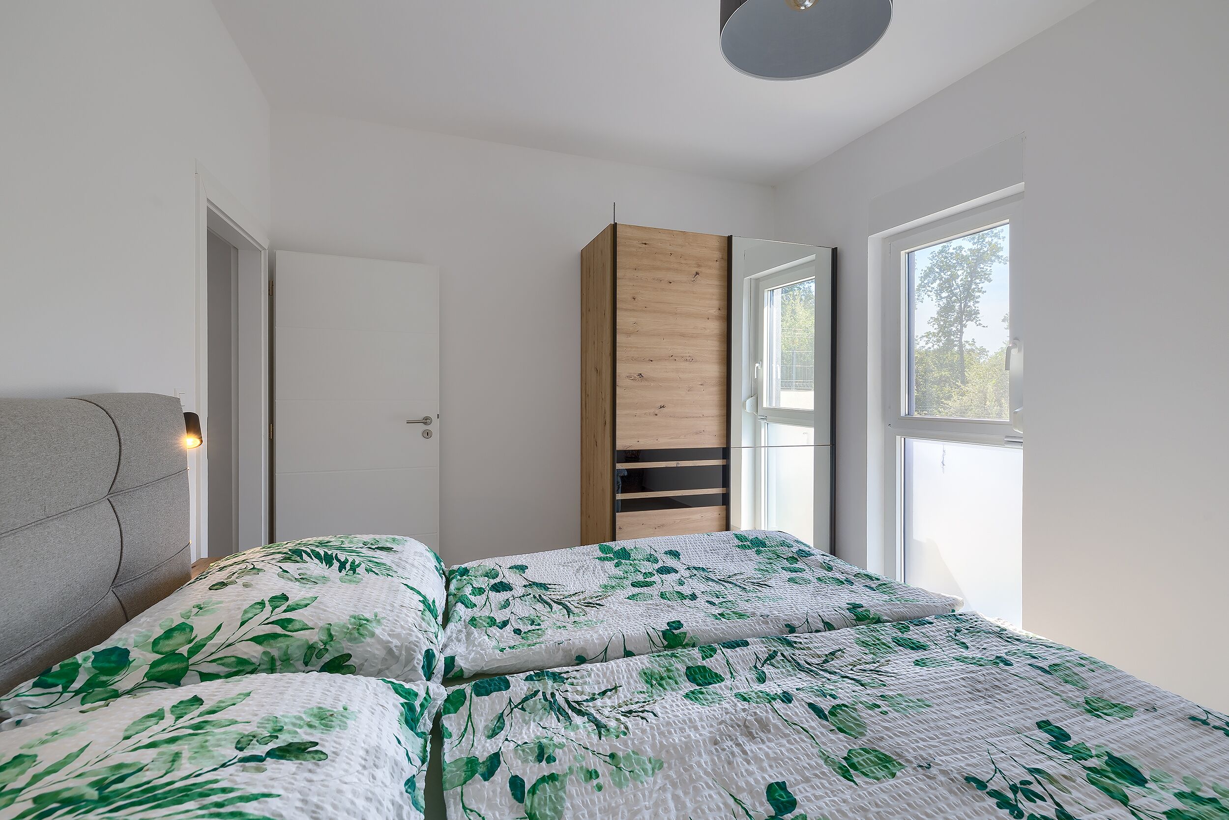 A bedroom with a bed, a wardrobe, and a window.