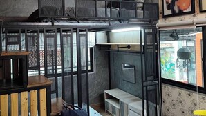 Un studio compact comprenant un lit superposé, un coin repas avec une table en bois et une kitchenette.