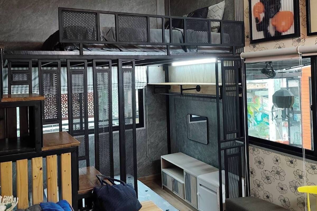 Een compact studio-appartement met een stapelbed, een eethoek met een houten tafel en een kitchenette.