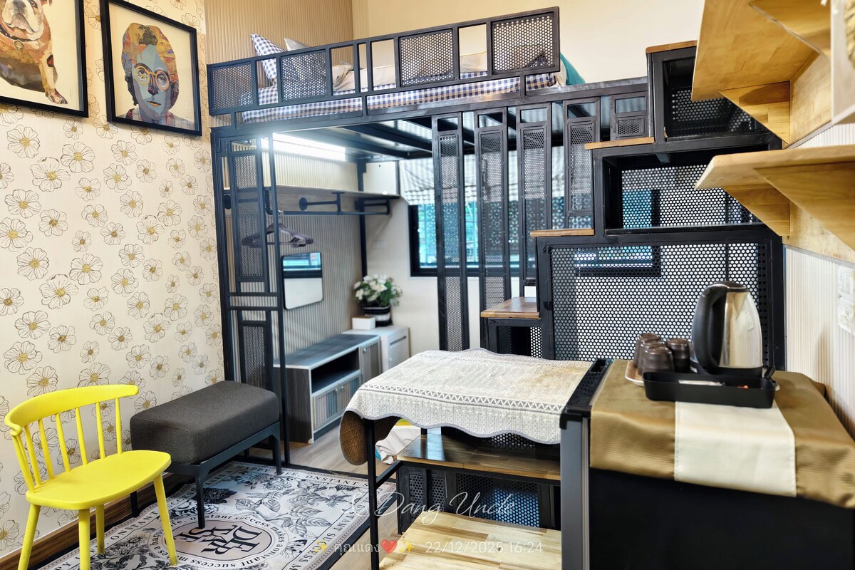 A compact, multi-level room with a bunk bed, a small desk, a chair, and a table with a tablecloth.
