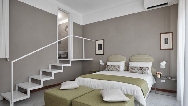 A bedroom with a staircase, a bed with two pillows, a nightstand, and a wall-mounted air conditioner. - Green H- Earth Suite for 2 persons (Florence)