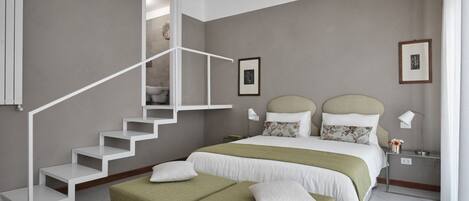 A bedroom with a staircase, a bed with two pillows, a nightstand, and a wall-mounted air conditioner.