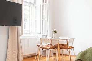 A room with a white table, two white chairs, a vase with flowers, a green blanket, and a white radiator. - Beautiful 2BR Apartment Near Rennweg (Vienna)