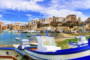 A coastal marina with boats docked, a clear sky, and buildings in the background. - Villa Romy with shared pool and garden - My Rental Homes (Castellammare Del Golfo)