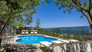 A swimming pool with lounge chairs and a stone wall. - Villa Romy with shared pool and garden - My Rental Homes (Castellammare Del Golfo)
