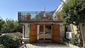 A stone building with a wooden door and balcony. - Villa Romy with shared pool and garden - My Rental Homes (Castellammare Del Golfo)