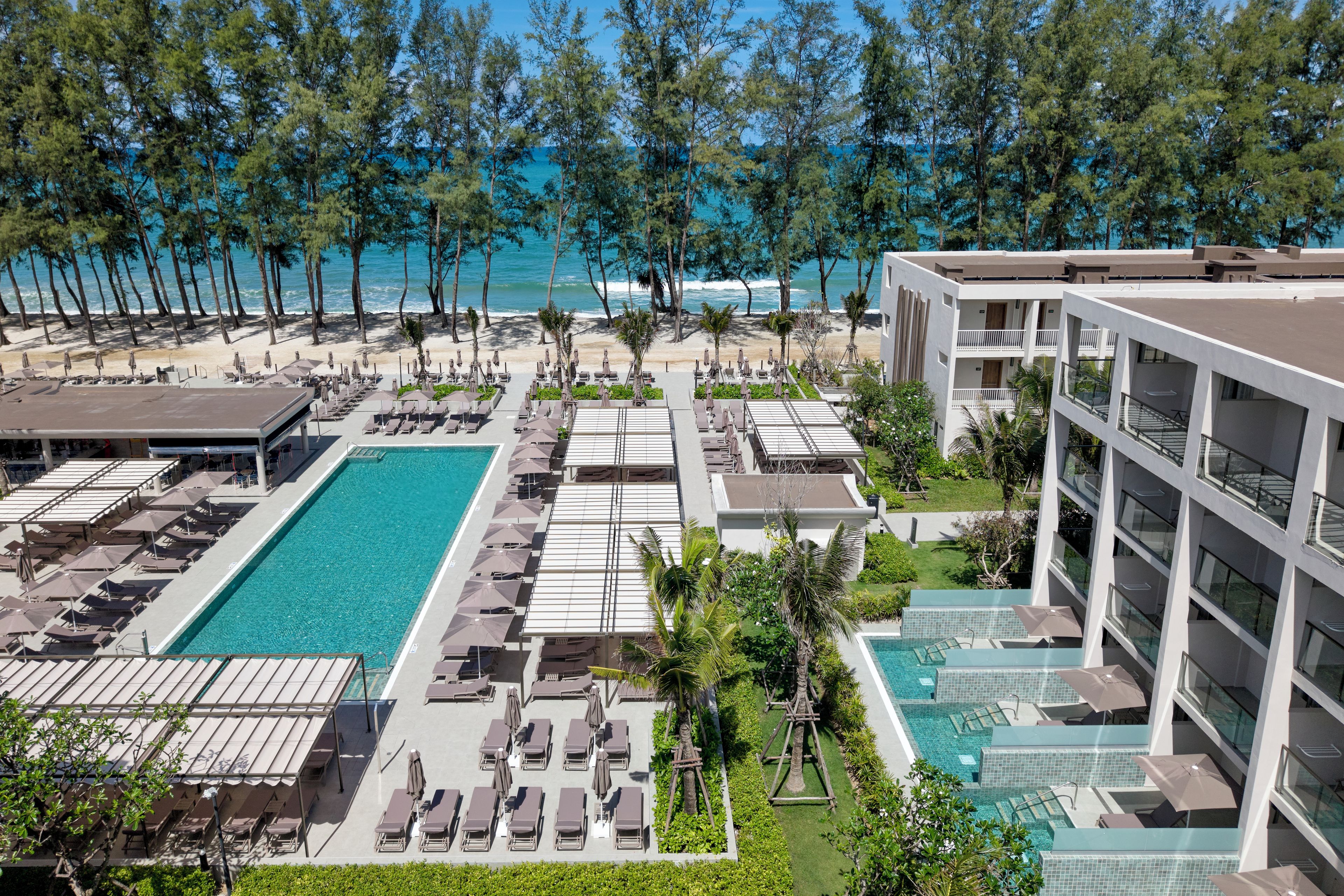 A resort with multiple swimming pools, sun loungers, and a beach view.